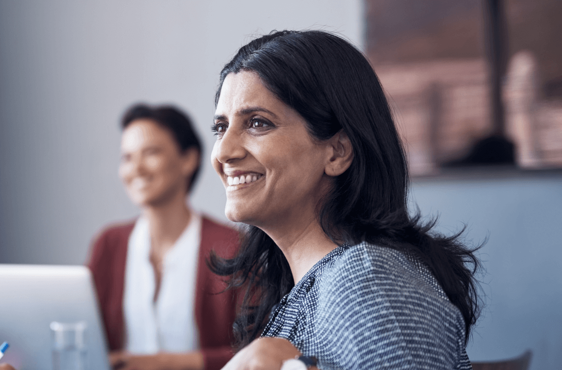 Woman sitting at a table, smiling, in a meeting to discuss the Your POrtfolio Life topics